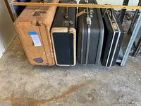 Four vintage suitcases lined up on the floor, showing their size and exterior condition