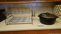 Photo of the metal dish rack and cast iron pot placed on a counter, showing overall condition and size.