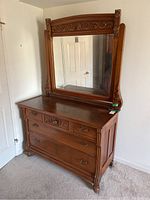 Full dresser with attached tilting mirror showing carved wood details and metal handles
