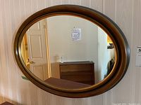 Front view of the oval wall mirror showing the full frame and reflective surface.