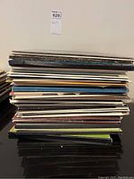 Stack of multiple vinyl record albums in cardboard sleeves.