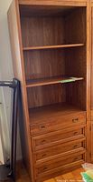 Front view of Sklar-Peppler bookshelf showing three shelves and four drawers with brass handles, wood grain finish.