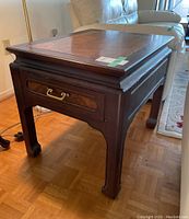 Side angle view of wood side table showing drawer with metal pull and legs.