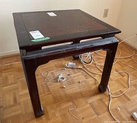 Full view of wood side table showing dark finish, square top with burled wood inlay, and slightly curved legs; some surface wear and finish flaws visible.