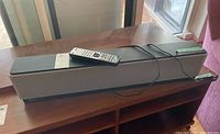 Yamaha YSP-800 sound bar front and top angled view with remote and wire on a wooden table.