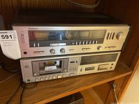 Front view of Technics stereo receiver SA-225 stacked on top of M51 cassette deck showing buttons and knobs in silver finish on wood shelf.