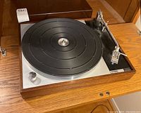 Front view of turntable showing plinth, platter mat, tonearm and dust cover