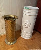 Two umbrella stands side by side, white ceramic and gold metal