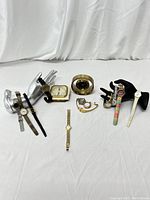 Wide shot of 9 vintage wristwatches displayed on silver and black hand-shaped stands alongside a vintage Taylor Humidiguide thermometer and humidity gauge in Art Deco style.