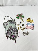 Full lot showing vintage enameled mesh purse, floral brooch, enamel pins, small gold-tone pins, and silver-tone brooches on white background.