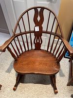 Front view of antique wooden rocking chair showing curved backrest and carved central splat.