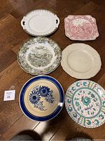 Top view of six assorted decorative china plates placed on wooden floor showing colors and designs.