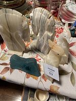 Marble horse head bookends with natural stripes, two carved birds, and green glass carving piece displayed on a table.