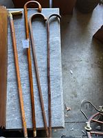 Four wooden canes on a gray surface, showing different curved handles and finishes.
