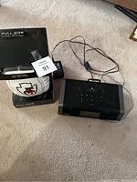 Full size Kansas City Chiefs football and black iHome stereo player with cables placed side by side on carpet.