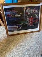 Framed print displayed on carpet, showing night scene with AMC cars, Rosie's Diner sign, gas pumps and American diner building details.