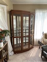 Full front view of the oak display cabinet showing the wood finish and glass shelving behind closed doors.