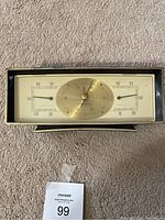 Front view of mid-century modern weather monitor on carpet, displaying barometer, thermometer, and hygrometer dials.