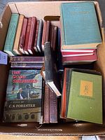 Top view of box filled with multiple hardcover books including 'Quo Vadis' and 'The Good Shepherd'