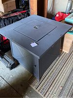 Full angled view of square metal fire pit table with closed top