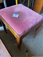 Sewing bench with pink velvet cushioned removable top showing wear, with wooden frame and legs visible.