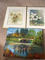 Image showing all three paintings together: two framed floral watercolors and one unframed oil landscape painting.