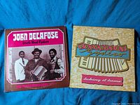 Photo showing front covers of two Zydeco vinyl records: John Delafose's 'Uncle Bud Zydeco' and Buckwheat Zydeco's 'Taking It Home'.