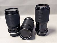 Three black camera lenses positioned upright and laying down showing size and shape