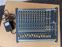 Behringer Eurorack MX 2642A mixing console laid flat with power supply and cable visible.
