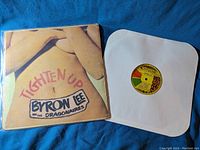 Vinyl album cover and record with colorful label laid on blue fabric background