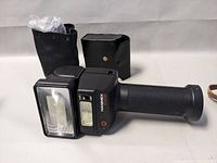 Hanimex P2400 handheld camera flash with protective case and accessories on white background.