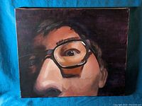 Full view of original stretched canvas painting showing the close-up face with glasses against a dark background