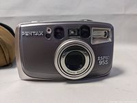 Front view of Pentax Espio 95S compact camera showing lens, flash, and Pentax branding.