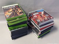 Front view showing total of 14 game cases stacked, including Xbox 360 and PlayStation 2 games. Gears of War 3 Xbox 360 case is visible on top.