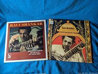 Front covers of two Ravi Shankar vinyl records laid side by side on a blue fabric.