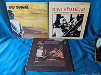 Three vinyl record albums featuring Ravi Shankar, two solo and one collaboration with Yehudi Menuhin, arranged on a blue fabric surface.