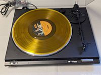 Front view of Technics turntable with yellow vinyl on platter and transparent dust cover