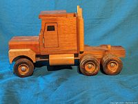 Side view of handmade wooden toy truck showing detailed cab and wheels.