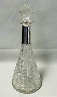 Full front view of the vintage cut crystal decanter with sterling silver neck band and faceted stopper.