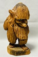Front view of hand carved wooden Norwegian troll figurine showing detailed face and texture.