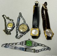 Overhead view of five vintage ladies watches on a neutral background