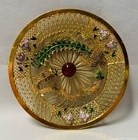 Front view of circular decorative wall art showing gold filigree dragon and phoenix around a central red glass bead.