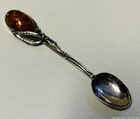 Full view of the 5 inch sterling silver spoon with amber stone on handle and decorative leaves.