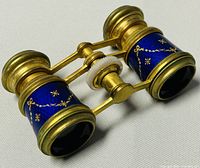 Front angle showing the blue enamel barrels decorated with gold floral motifs and brass hardware.