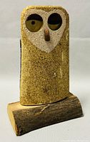 Front view of the carved wooden owl mounted on a rustic wood log base.