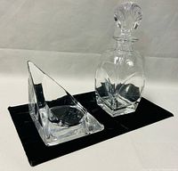 Image showing both the glass decanter with stopper and the triangular-shaped glass candleholder on a black surface