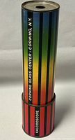Front view of cylindrical kaleidoscope showing vertical rainbow stripes and labeling 'Corning Glass Center - Corning, N.Y.' and 'Kaleidoscope'.