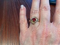 Ring on finger showing top view of heart-shaped red stone and diamond accents