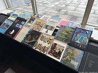 Overhead view of 16 art books arranged on a bench under a window