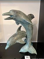 Front view of the bronze dolphin sculpture showing both dolphins in leaping pose